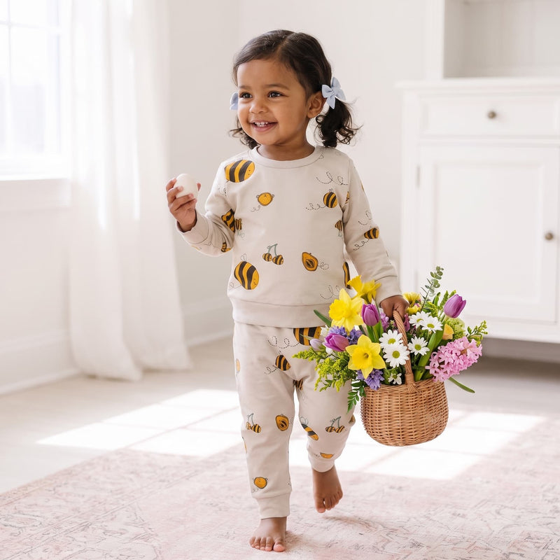 Toddler carrying a basket of flowers wearing the Bee Kind organic cotton t-shirt and harem joggers